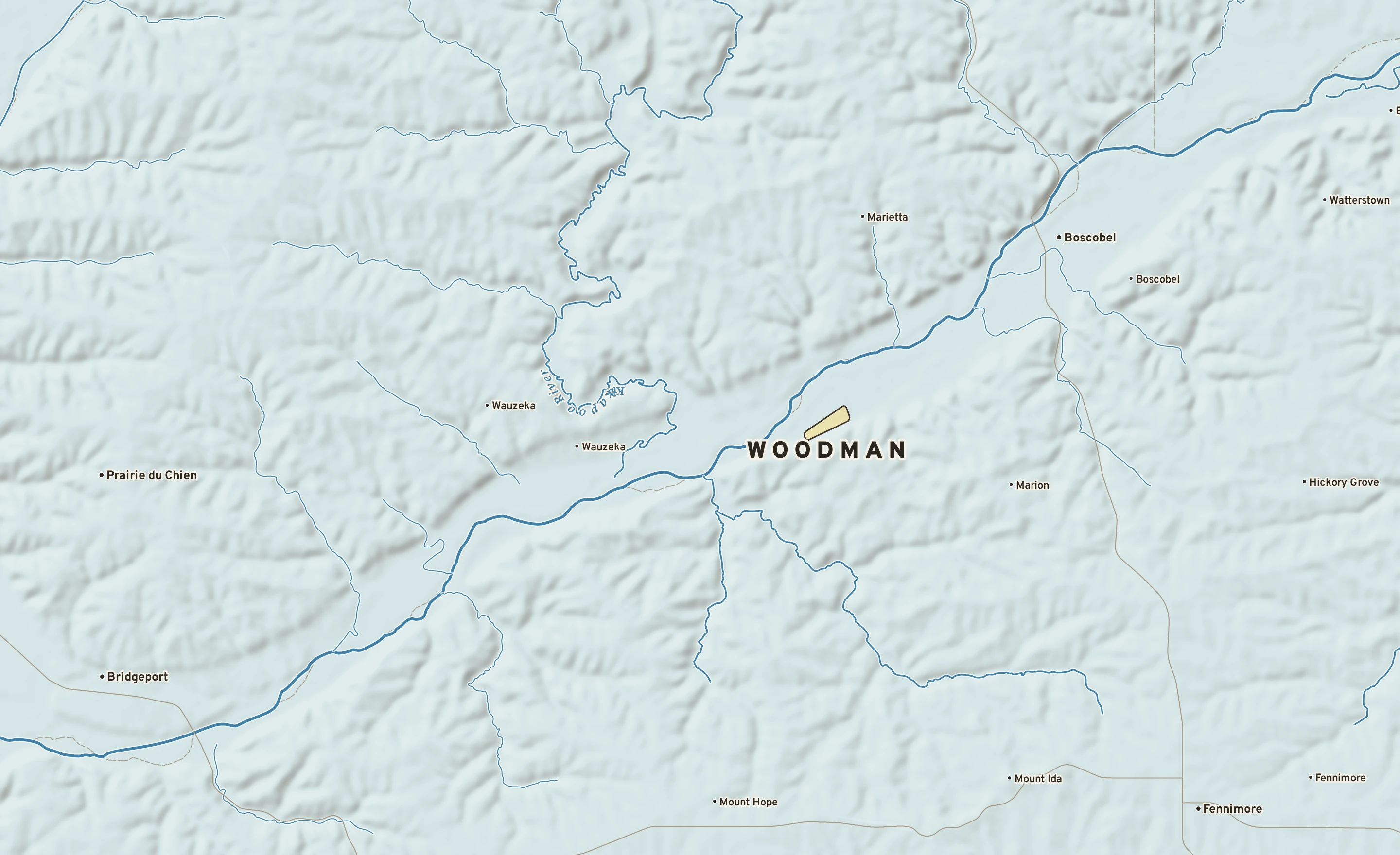 Shaded-relief atlas plate of Woodman, Wisconsin: rivers, roads, the city limits and where the water drains.